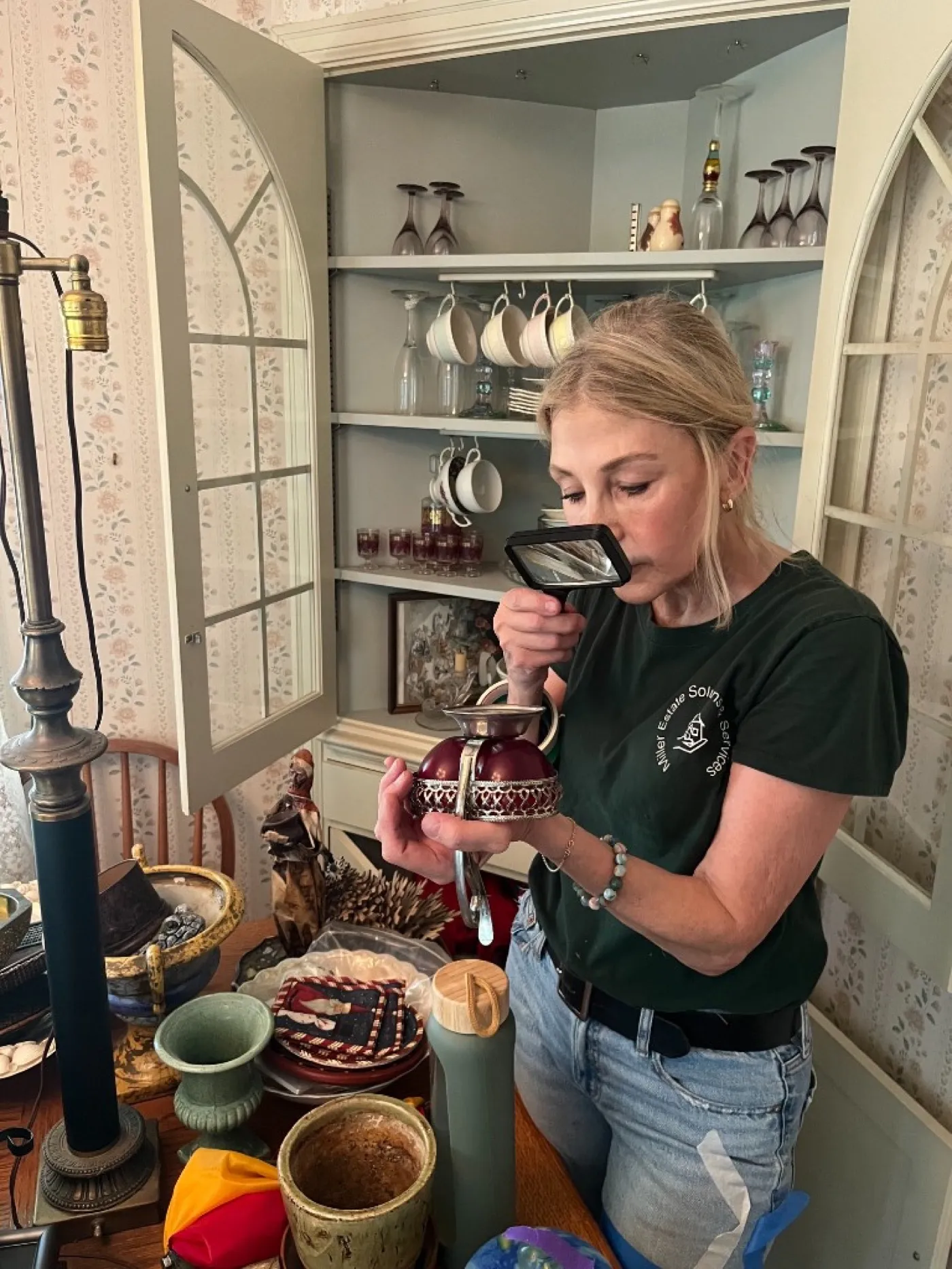 Laura Miller examining a fine glass piece with a magnifying glass during an estate appraisal