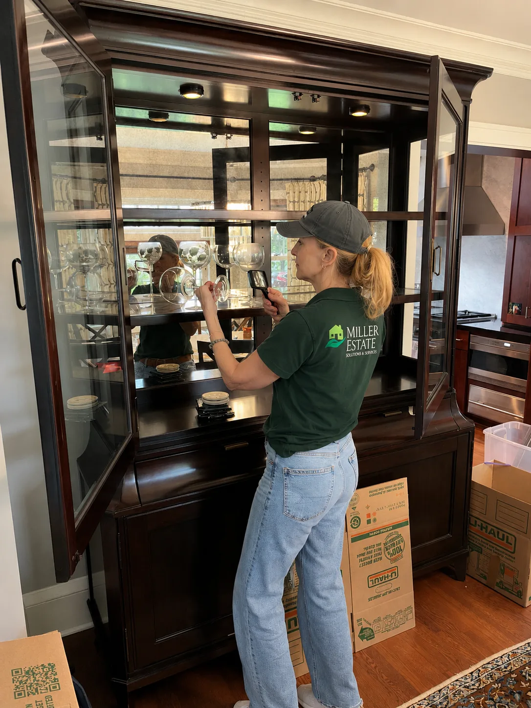 A Miller Estate Solutions team member examining crystal stemware with a magnifying glass while inventorying estate contents